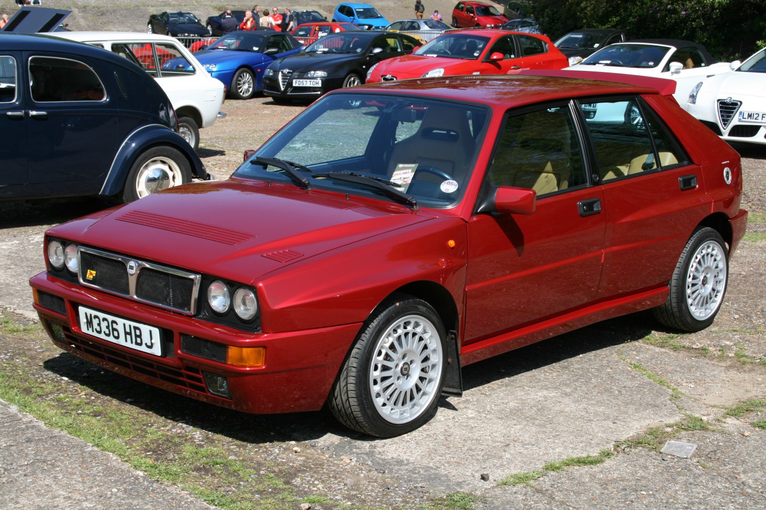 Red hatchback with quad round headlights and sporty alloy wheels