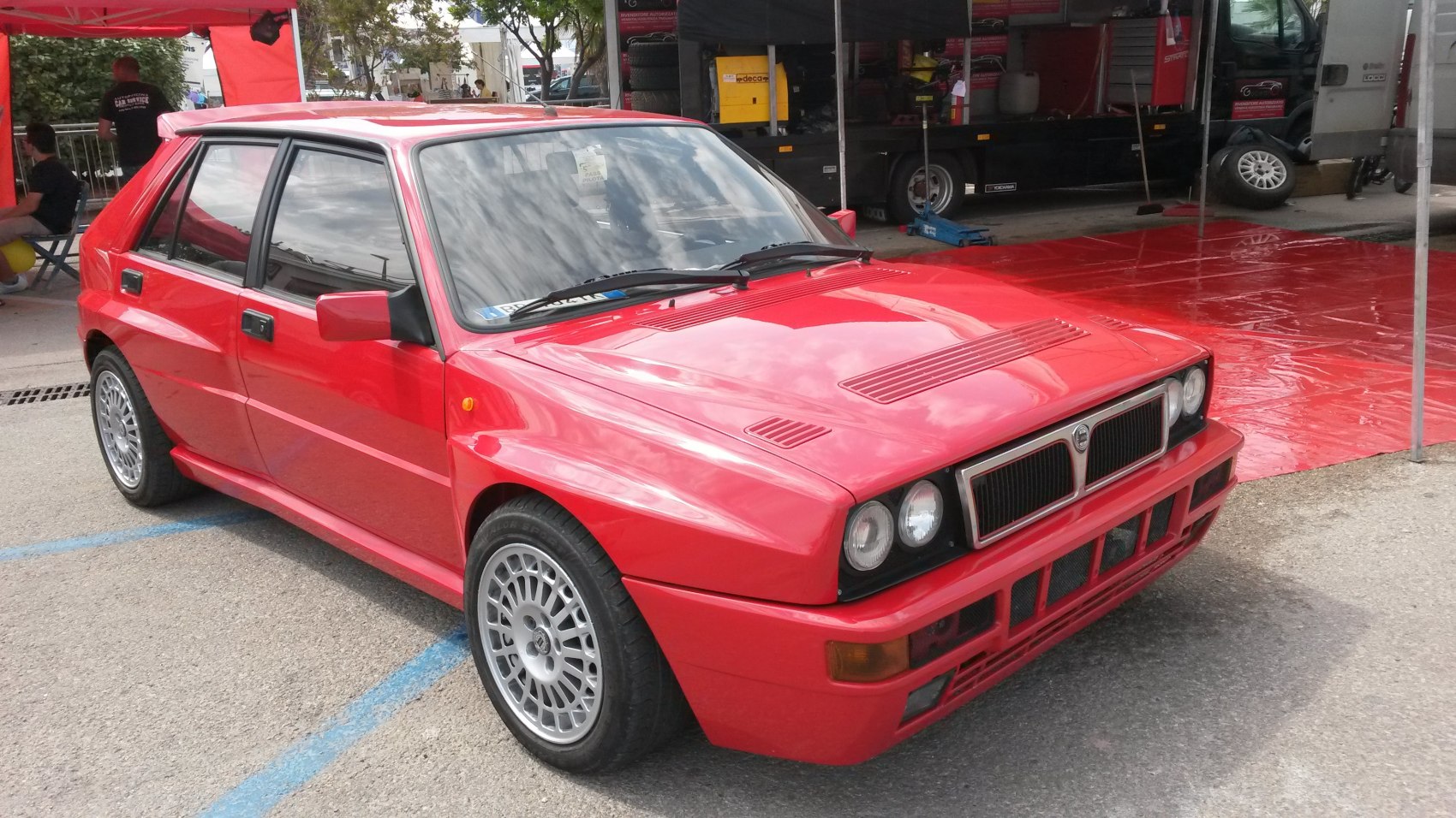 Red hatchback with quad headlights and alloy wheels