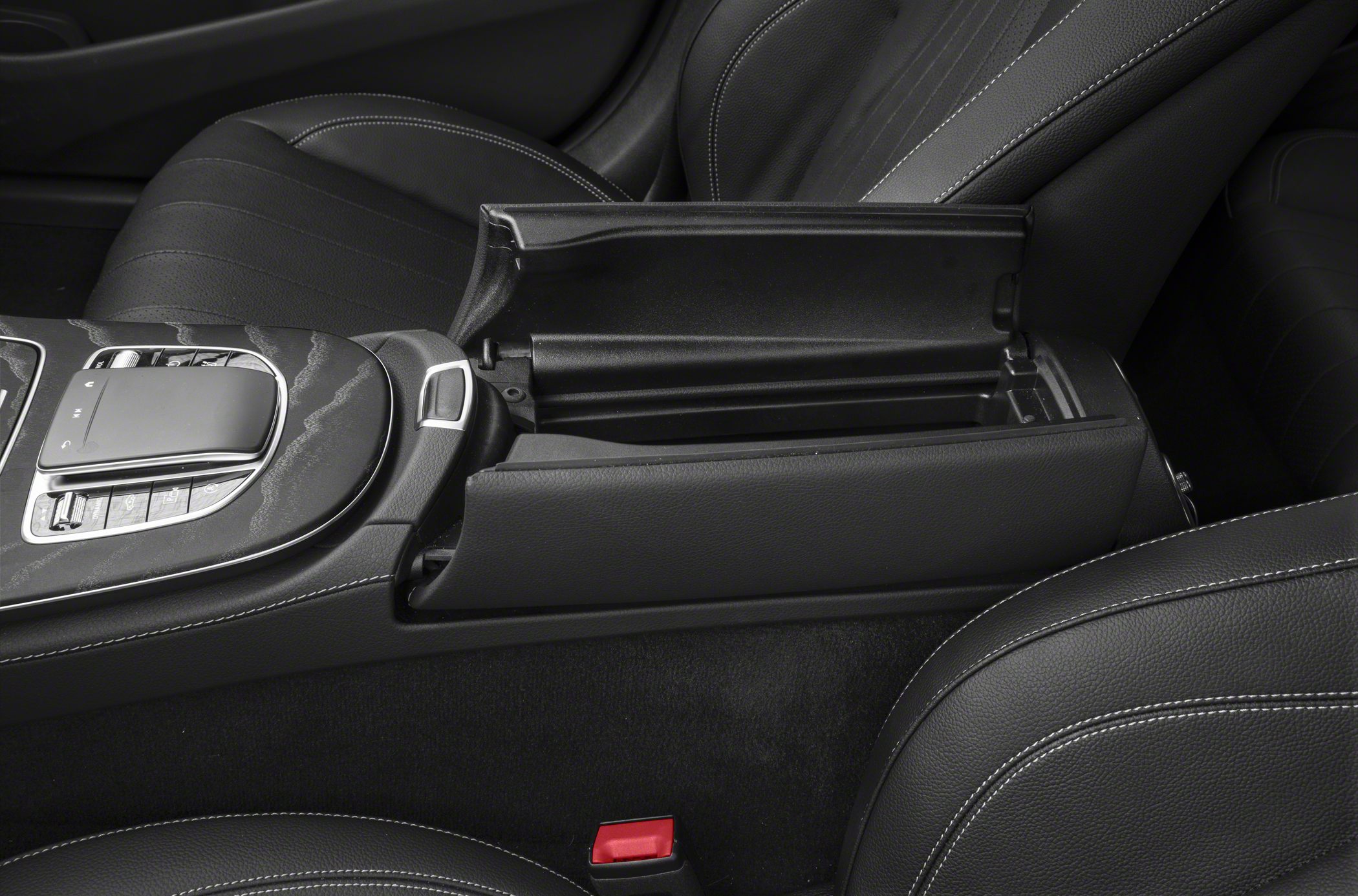 Open center console storage with control buttons between black leather seats