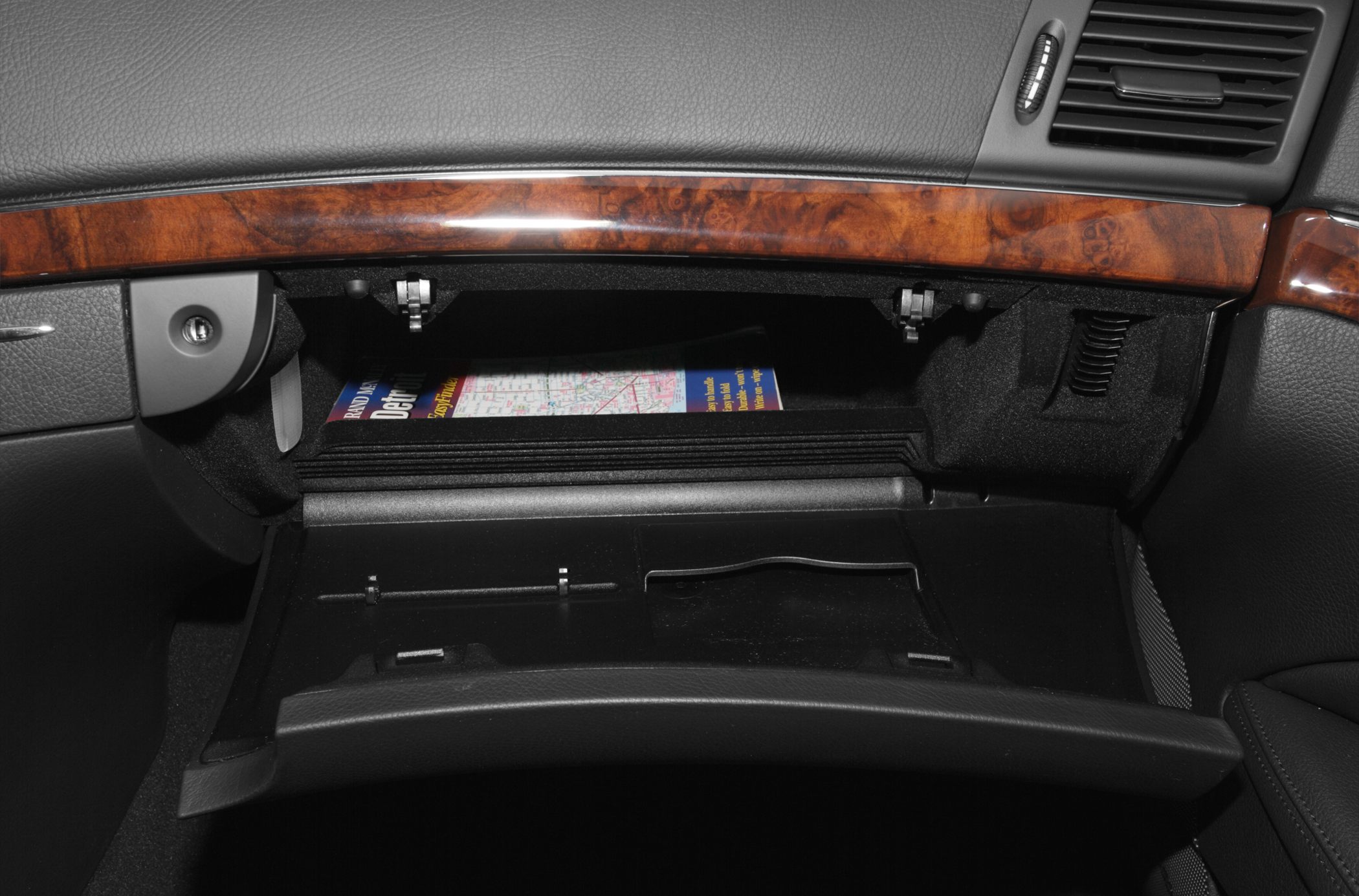 Open glove box with wooden trim and black interior