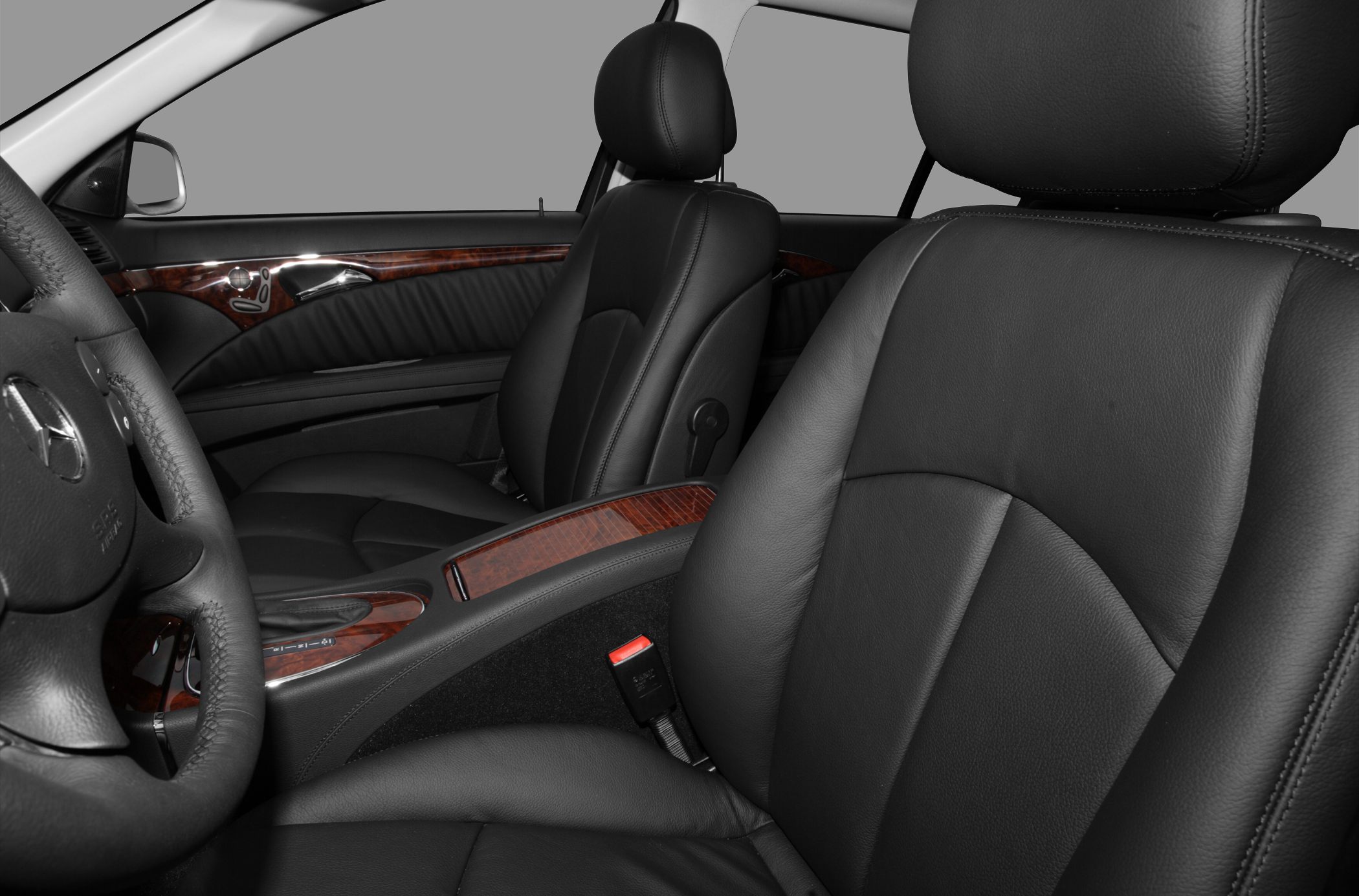 Black leather seats and wooden trim interior of car front cabin