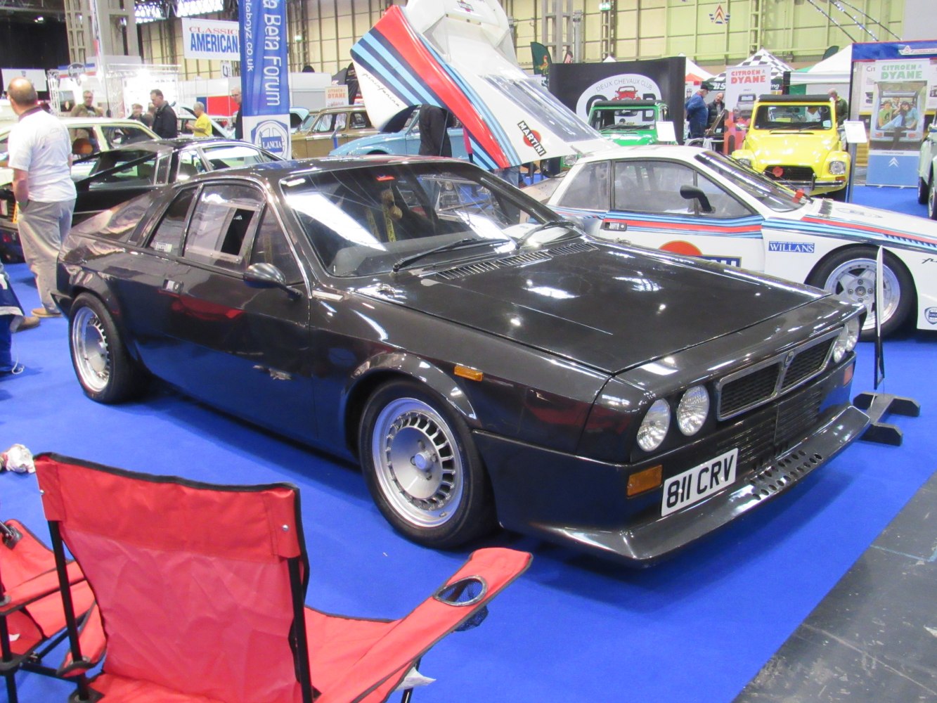 Black angular front sports coupe with dual round headlights and wide fenders