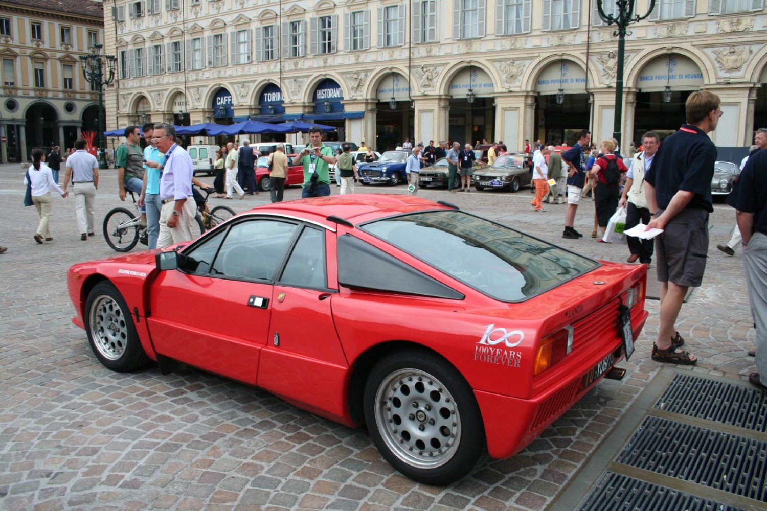 Rear side profile of a red rally car with angular body and distinctive wheel design