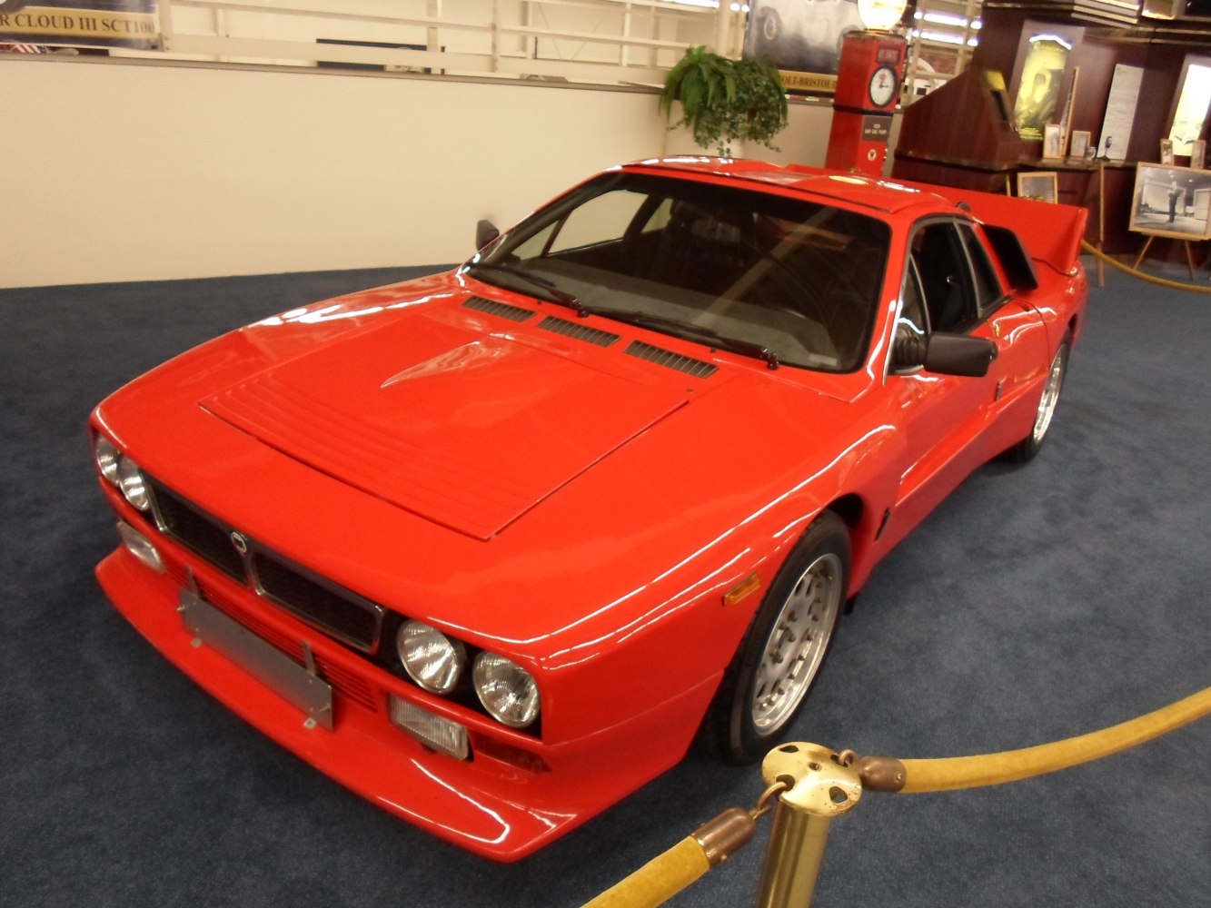 Red mid-engine vintage sports car with quad round headlights and sharp front grille