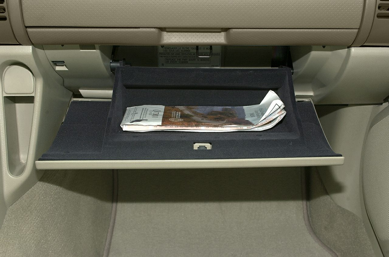 Open glove compartment with folded paper inside.