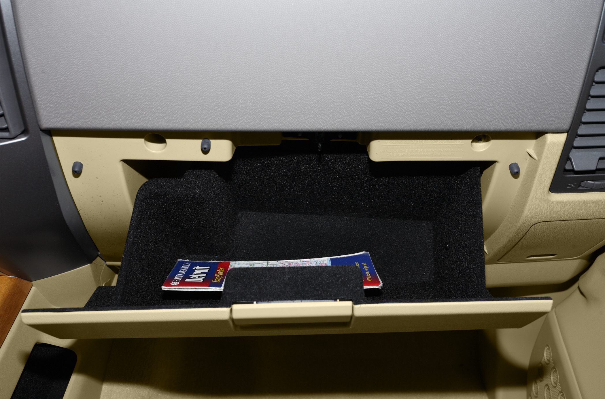 Glove compartment interior with map storage and beige dashboard panel.