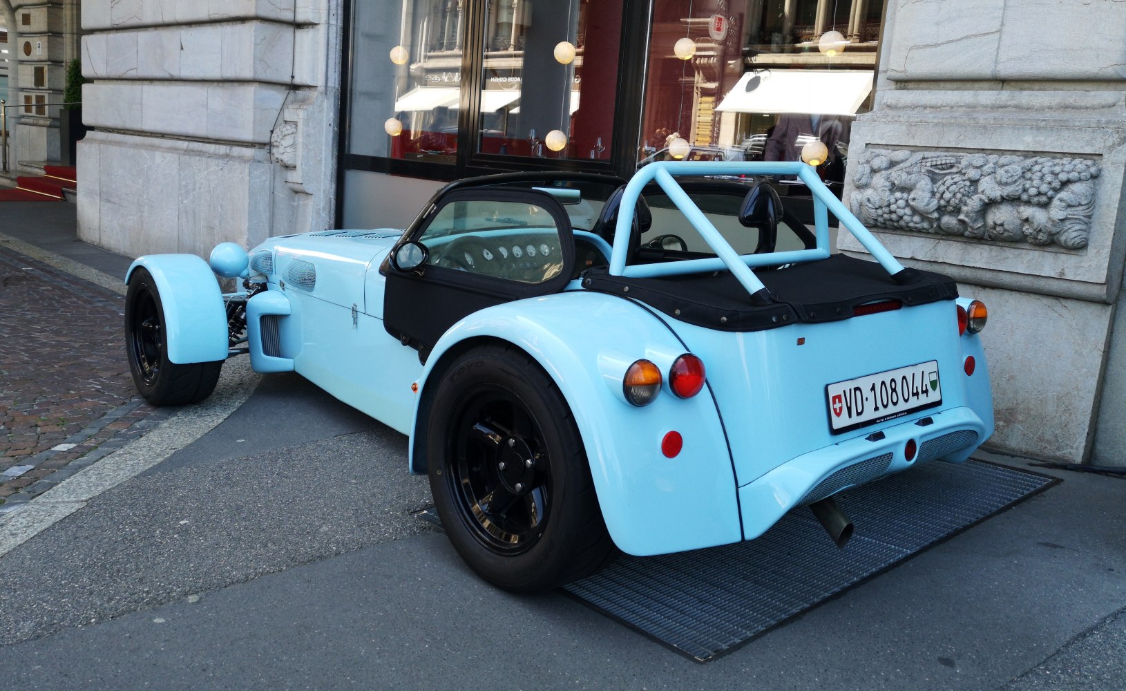 Rear view of a lightweight roadster with exposed wheels and tubular roll cage