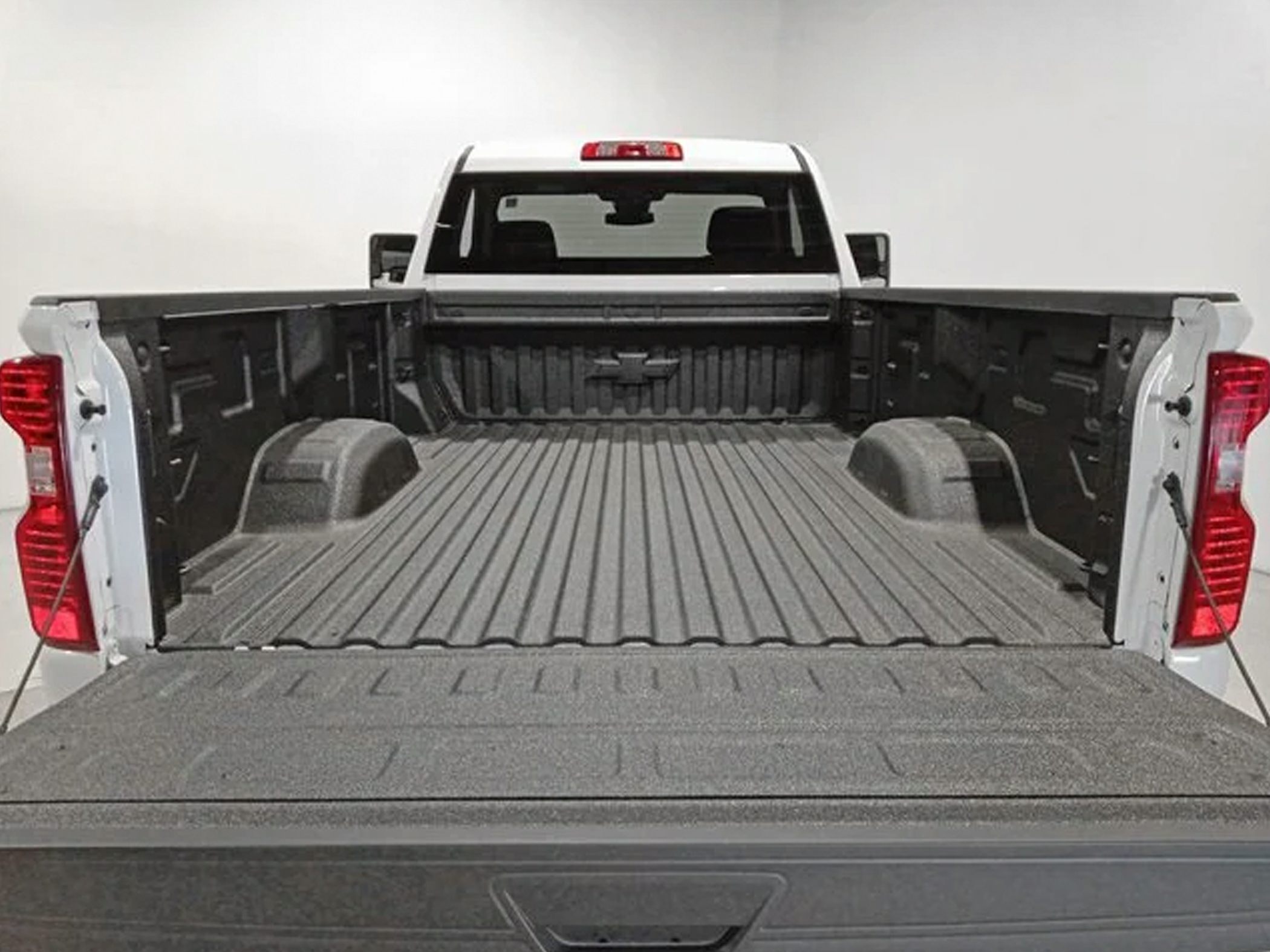 Durable protective bed liner covering empty truck bed interior with extended wheel wells and open tailgate