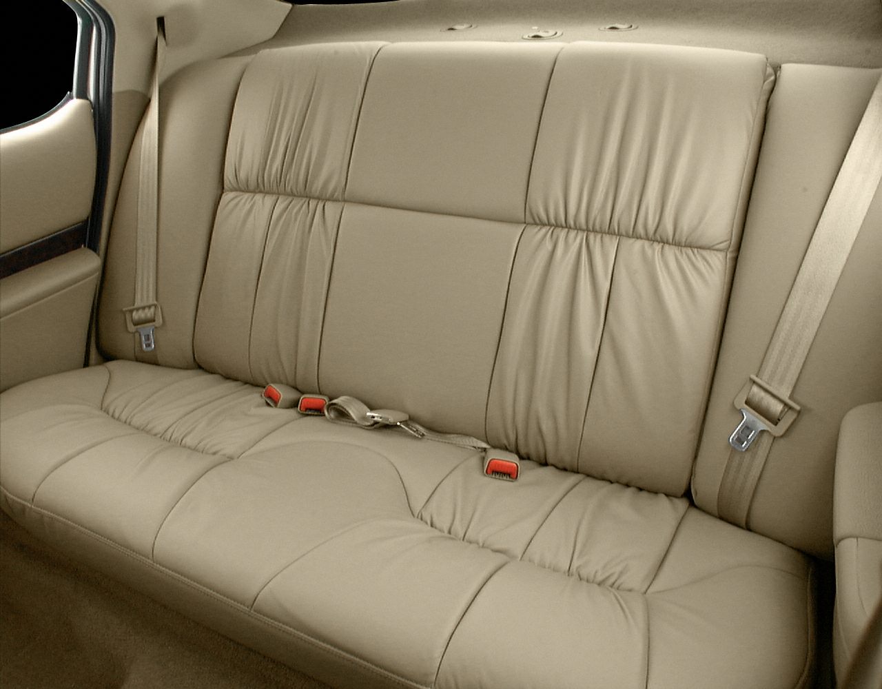 Beige leather rear seat interior with seat belts and stitching details