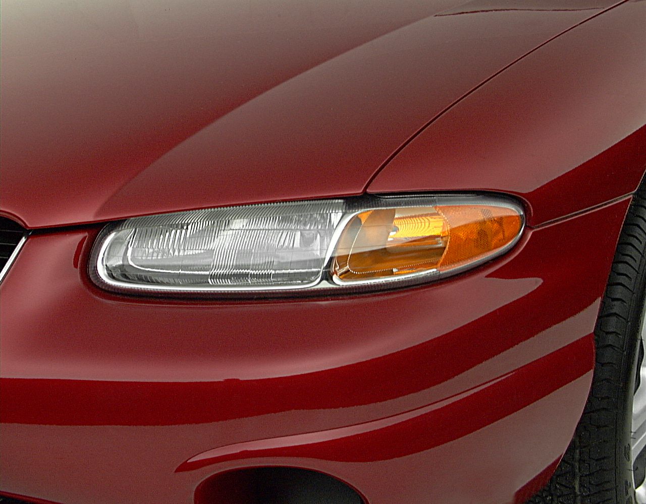Close-up of car headlight with amber turn signal and red front fender
