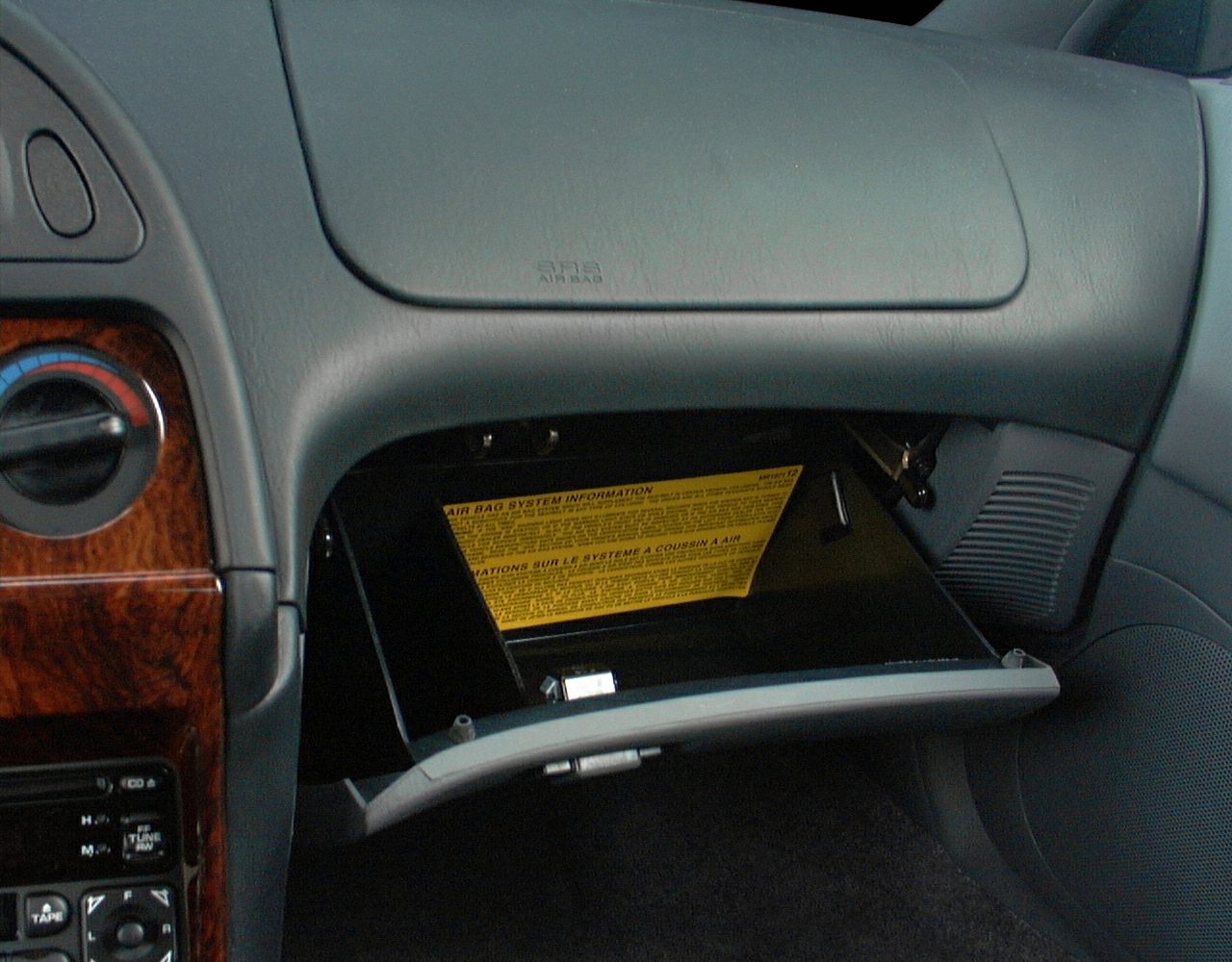 Open glovebox and dashboard with climate controls and wood trim