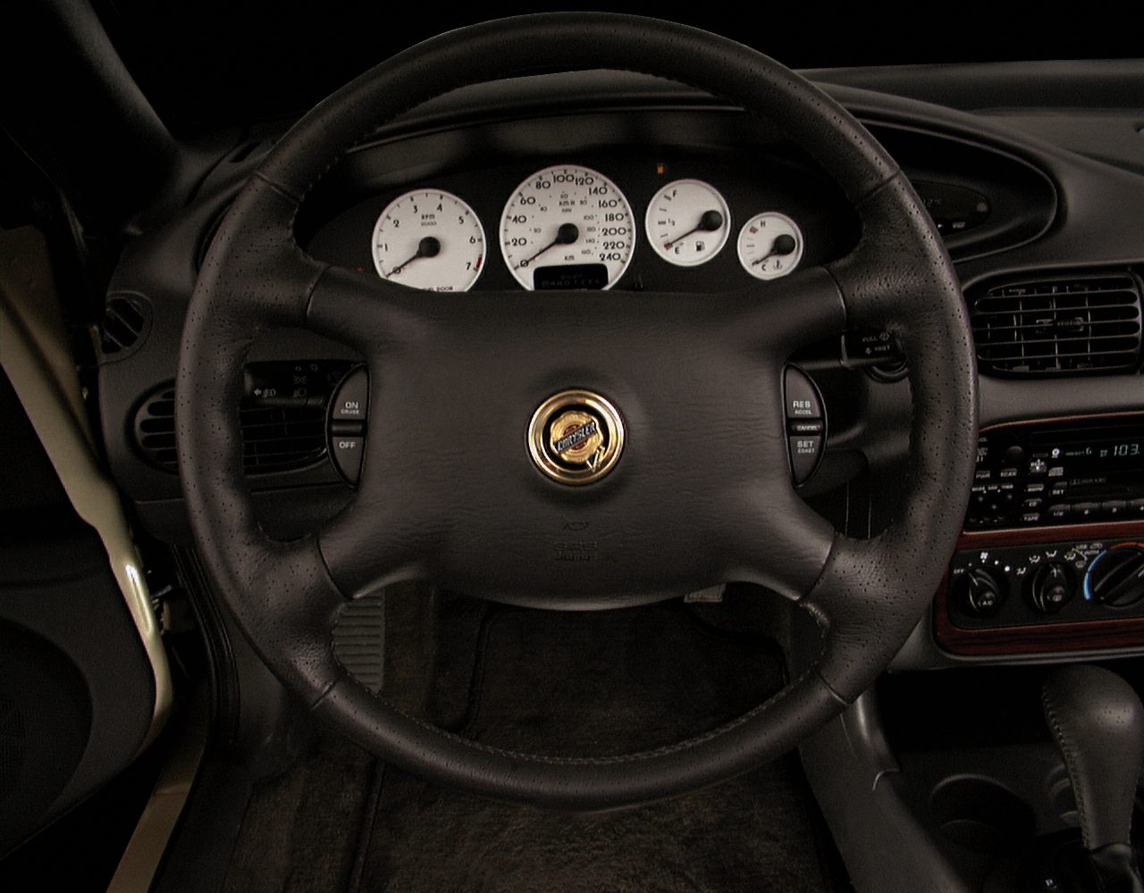 Black leather steering wheel with white gauges and cruise control buttons