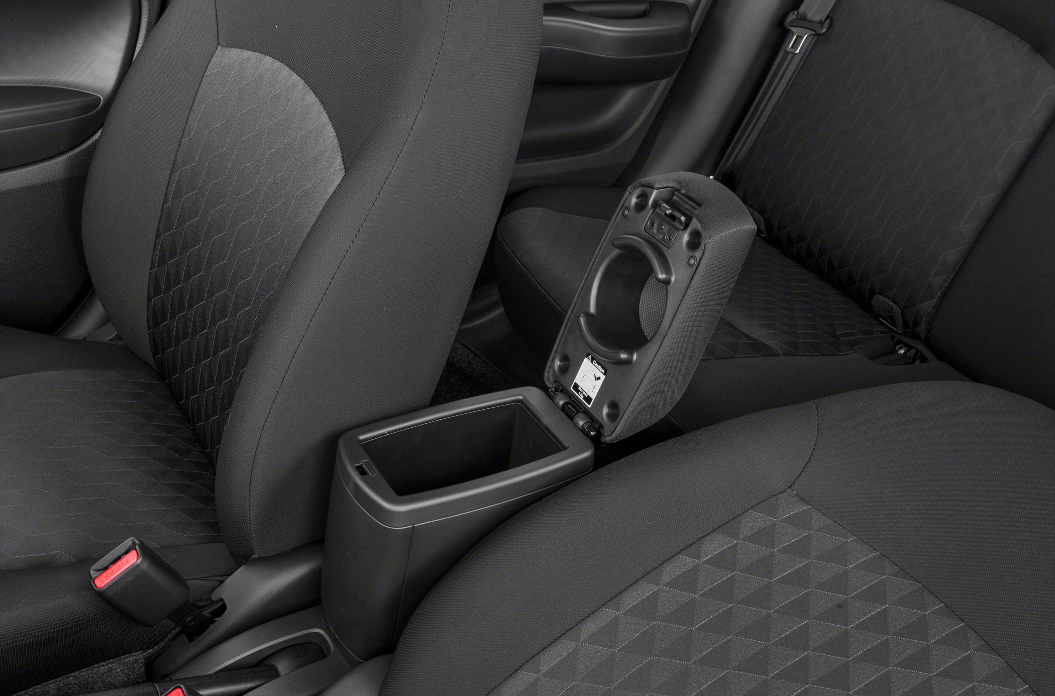 Open center console with cup holder and black fabric seats inside a compact hatchback