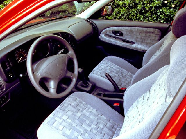 Compact car interior with cloth seats, manual transmission, and simple dashboard layout