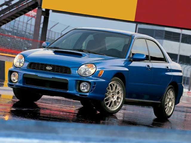 Blue hatchback with hood scoop and sporty alloy wheels on wet surface