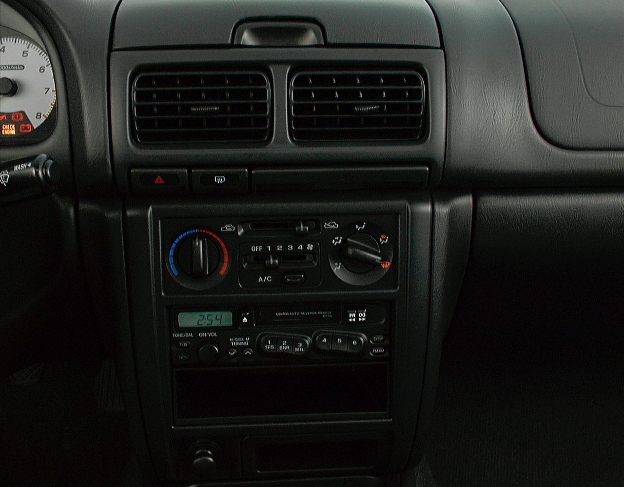 Dashboard air vents, climate control dials, and audio system in vintage car interior