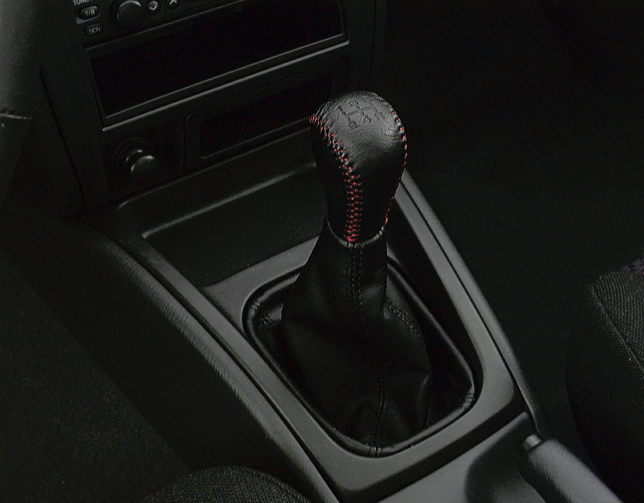 Manual transmission gear shifter with black leather and red stitching