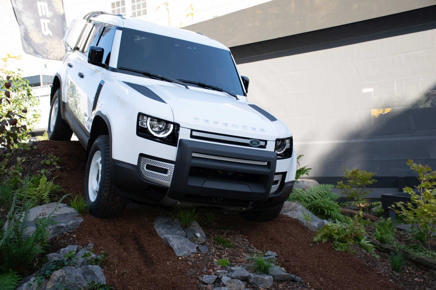 White off-road SUV with bull bar and rugged tires on rocky terrain