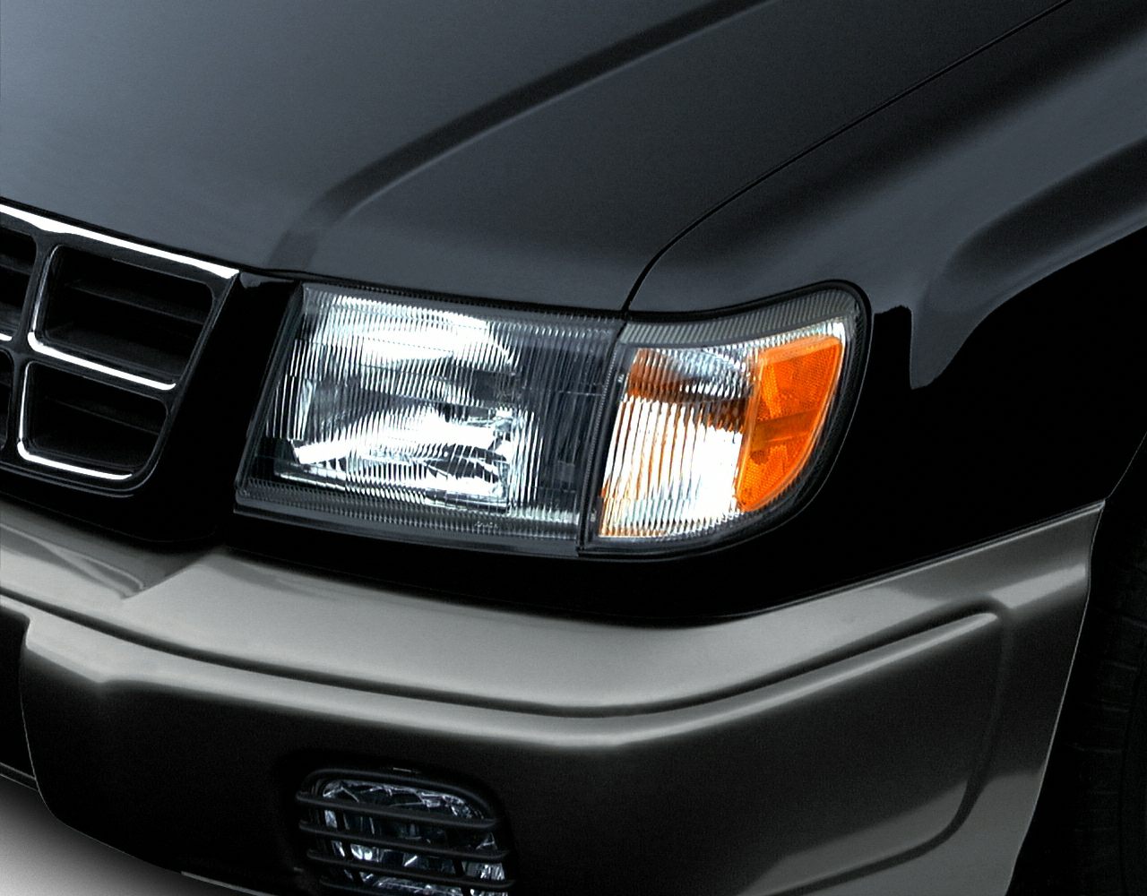 Close-up of front headlight and grill with turn signal and fog light