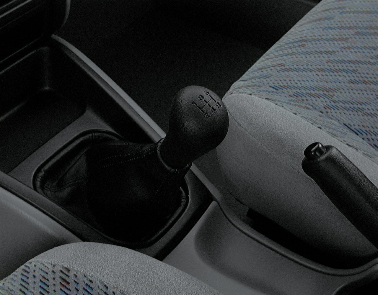 Manual gear shift with handbrake between fabric car seats