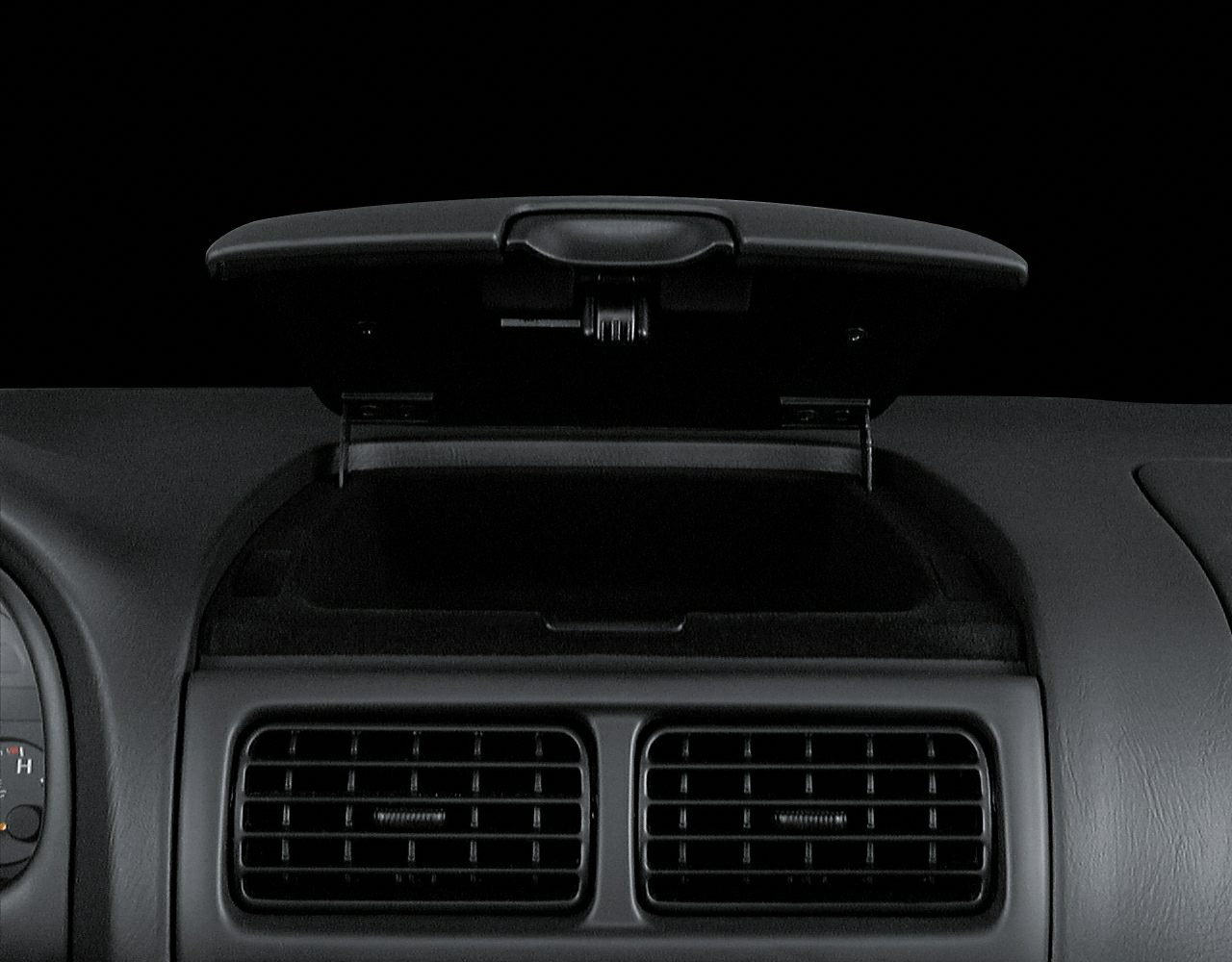 Dashboard storage compartment above dual air vents in black plastic