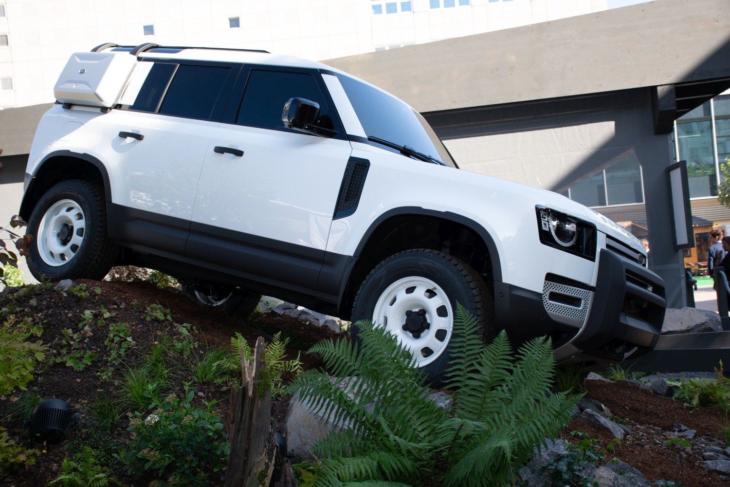 Off-road white SUV with rugged tires, roof rack, and rear spare storage box