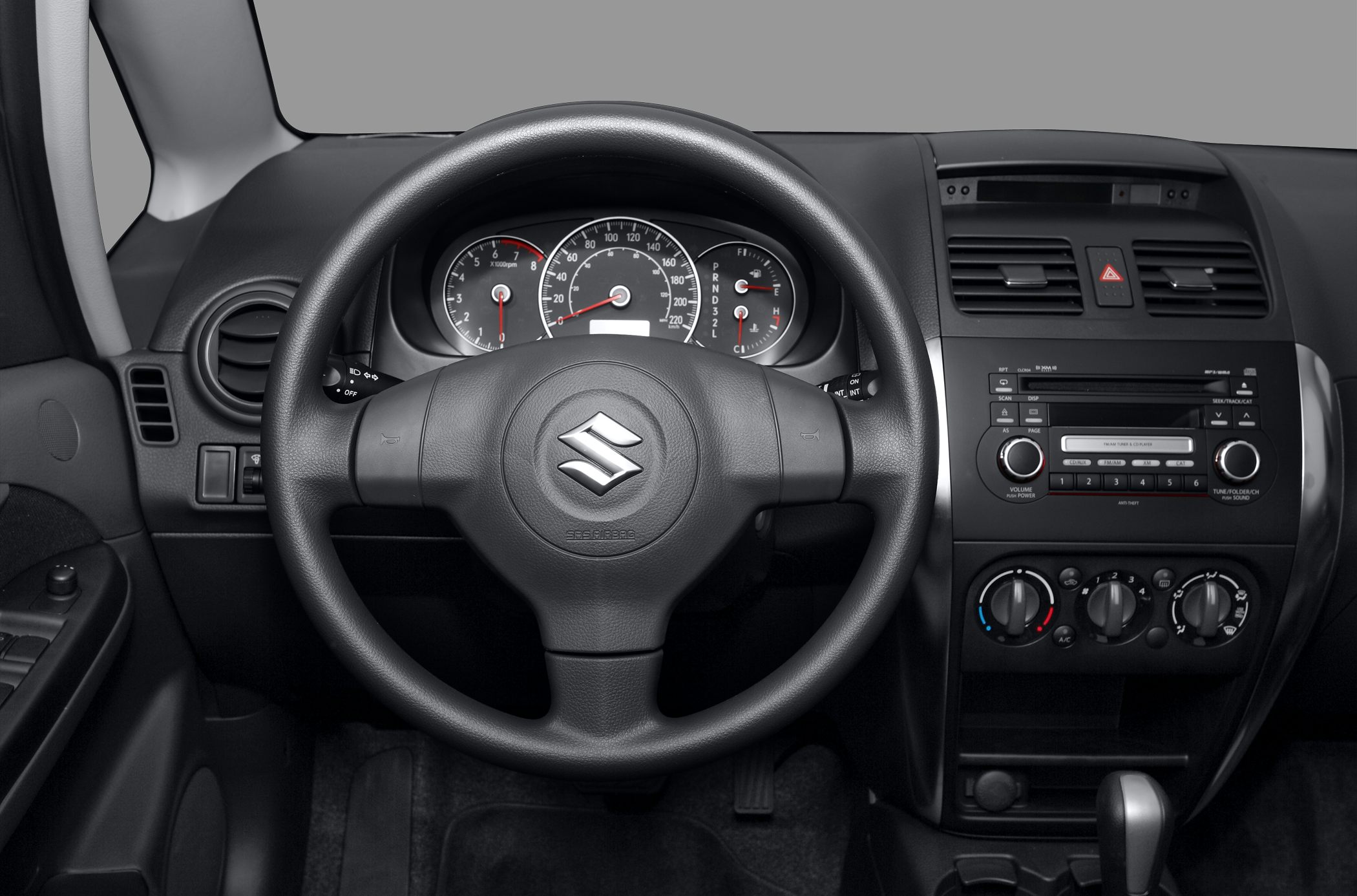 Car dashboard with analog gauges and multifunction steering wheel.