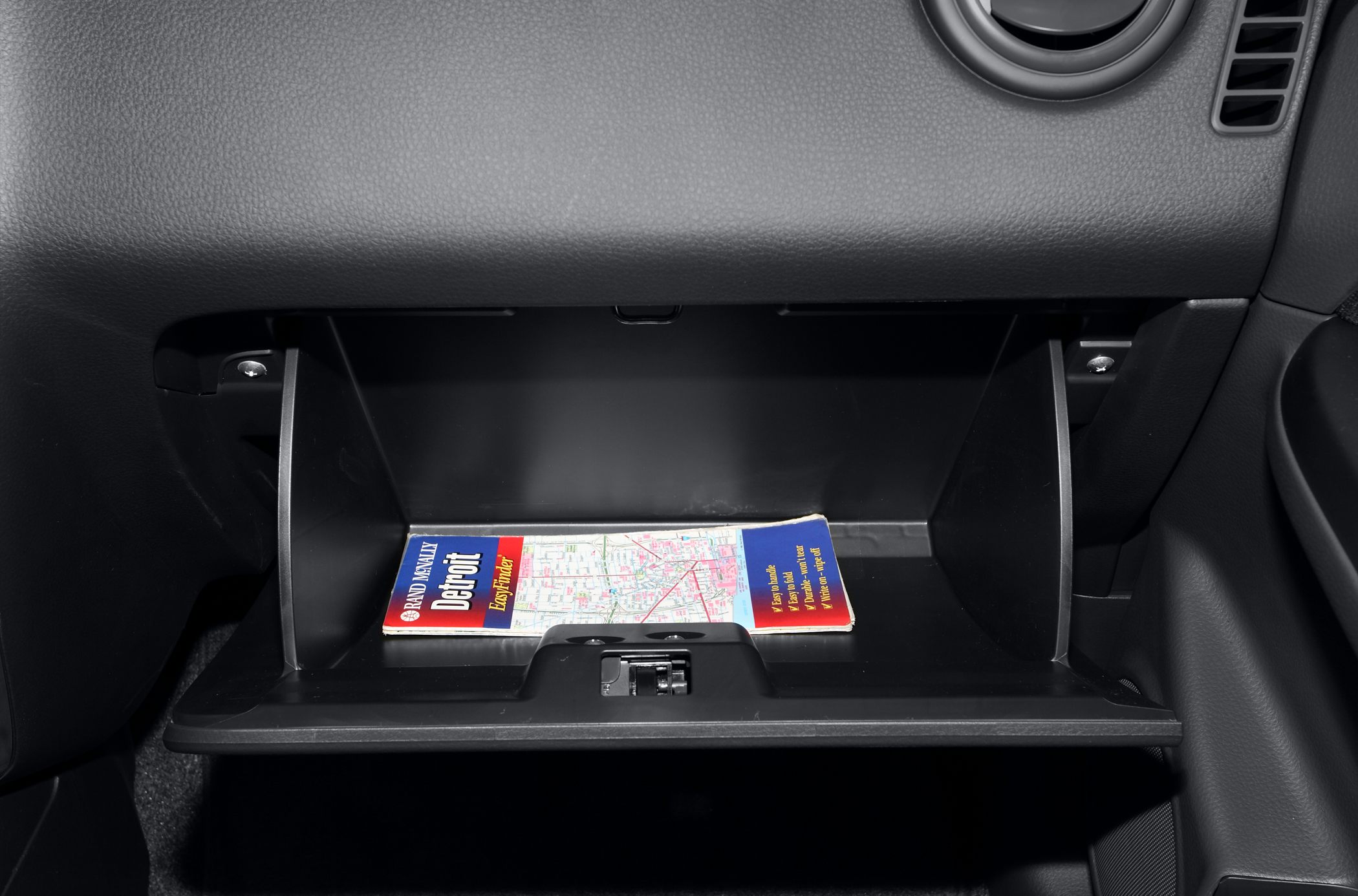 Open glove box compartment with road map inside car interior