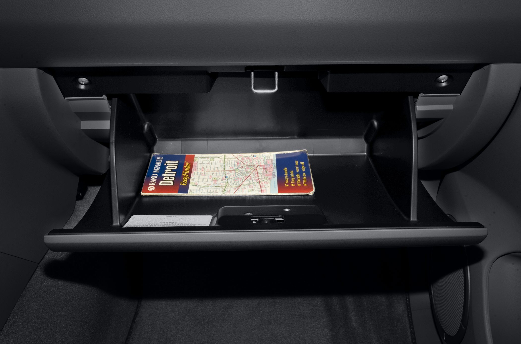 Open glovebox with storage compartment containing a map booklet.