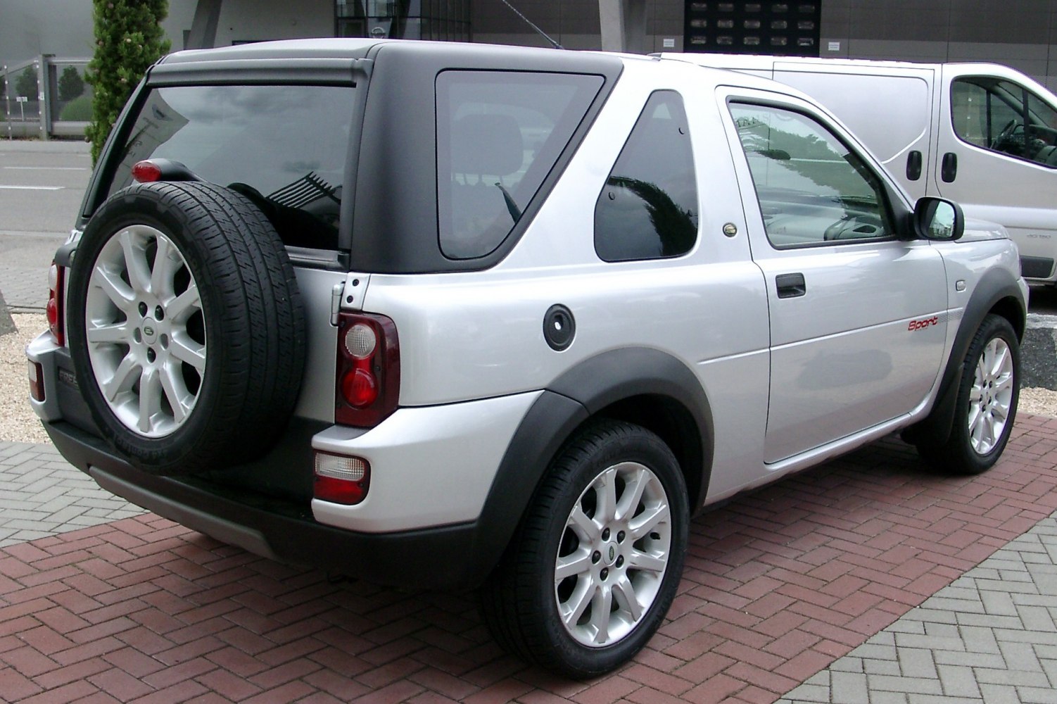 Rear and side view showing spare wheel on tailgate and 3-door compact SUV design