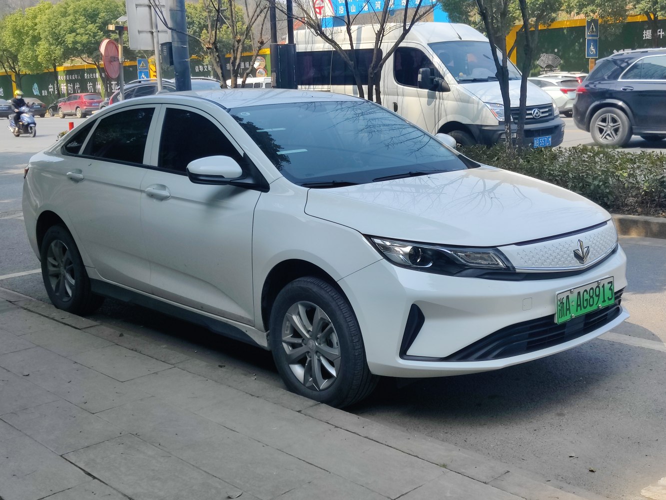 Sleek front and side profile of a white electric sedan with modern headlights.