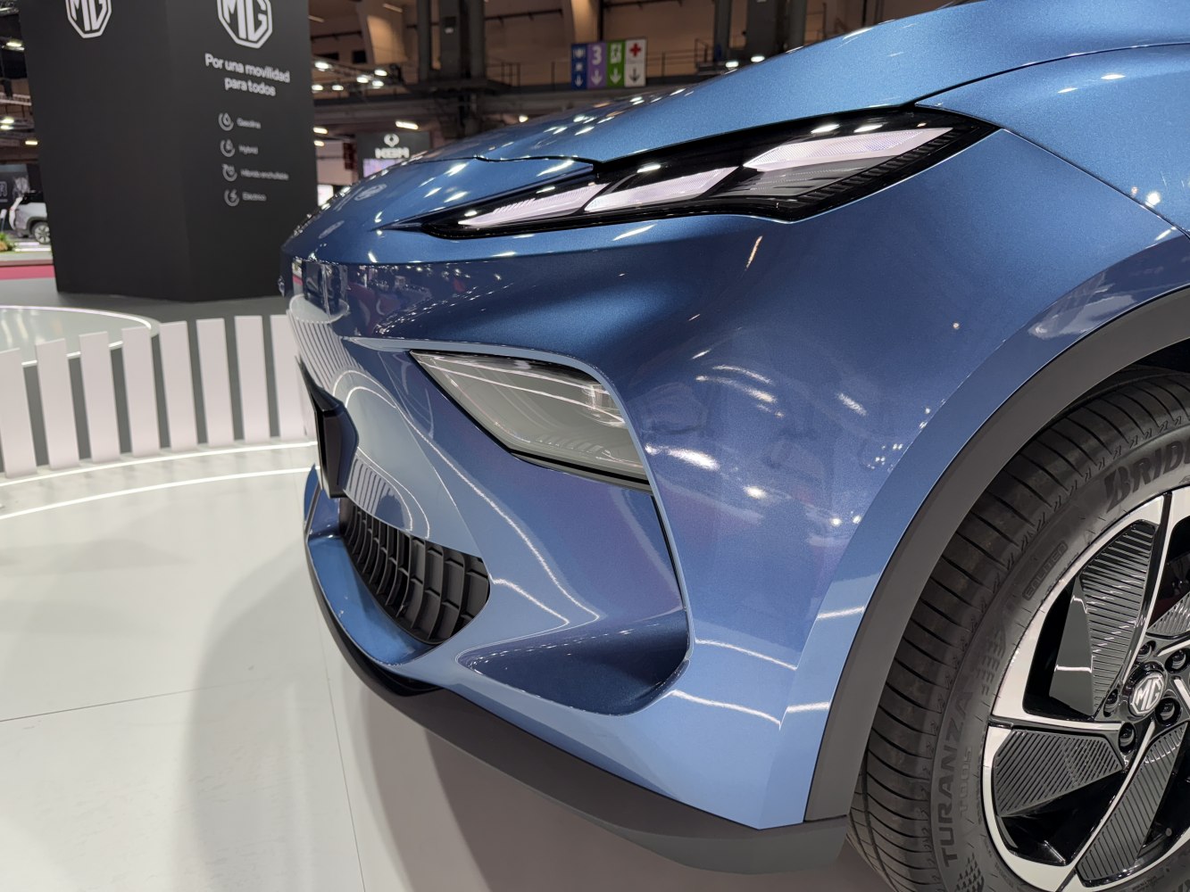 Close-up of front headlight and alloy wheel on blue electric SUV.