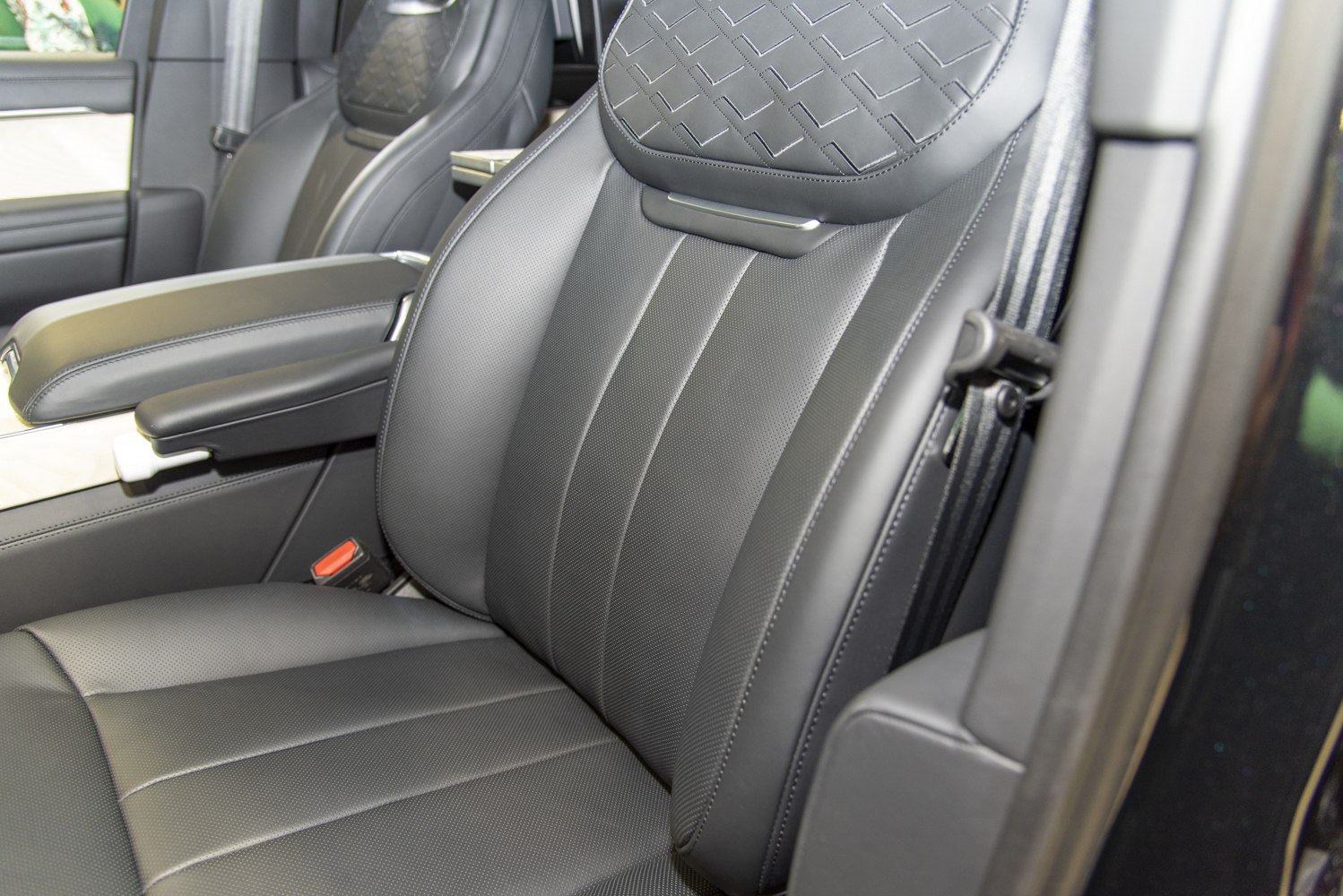 Black leather car seat with quilted headrest and armrest