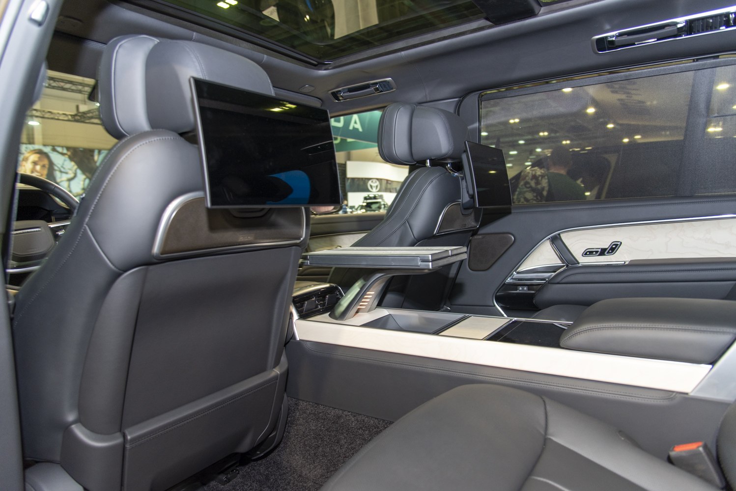 Rear passenger seats with entertainment screens and foldable tray table