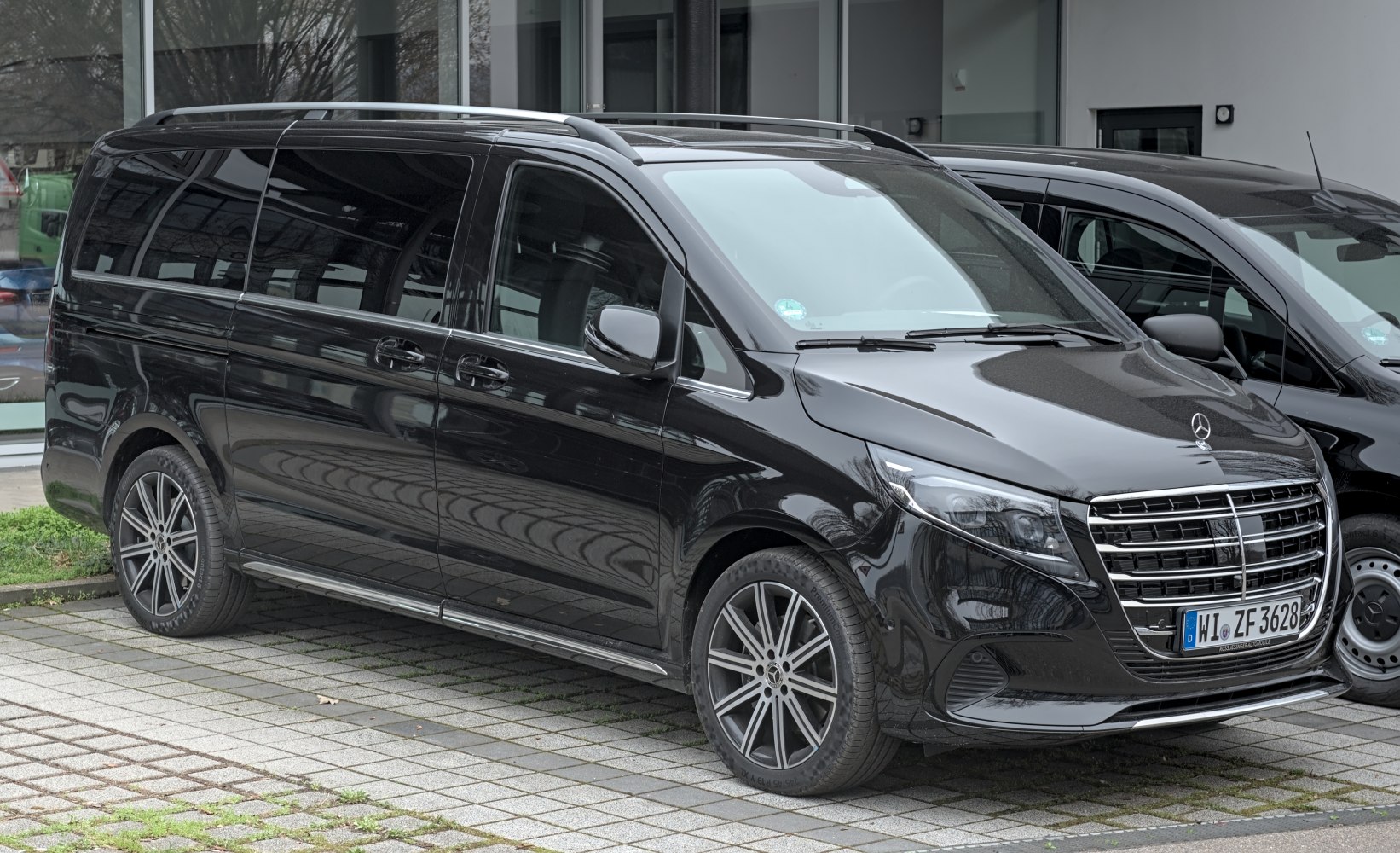 Front-side view of sleek black long van with alloy wheels and roof rails
