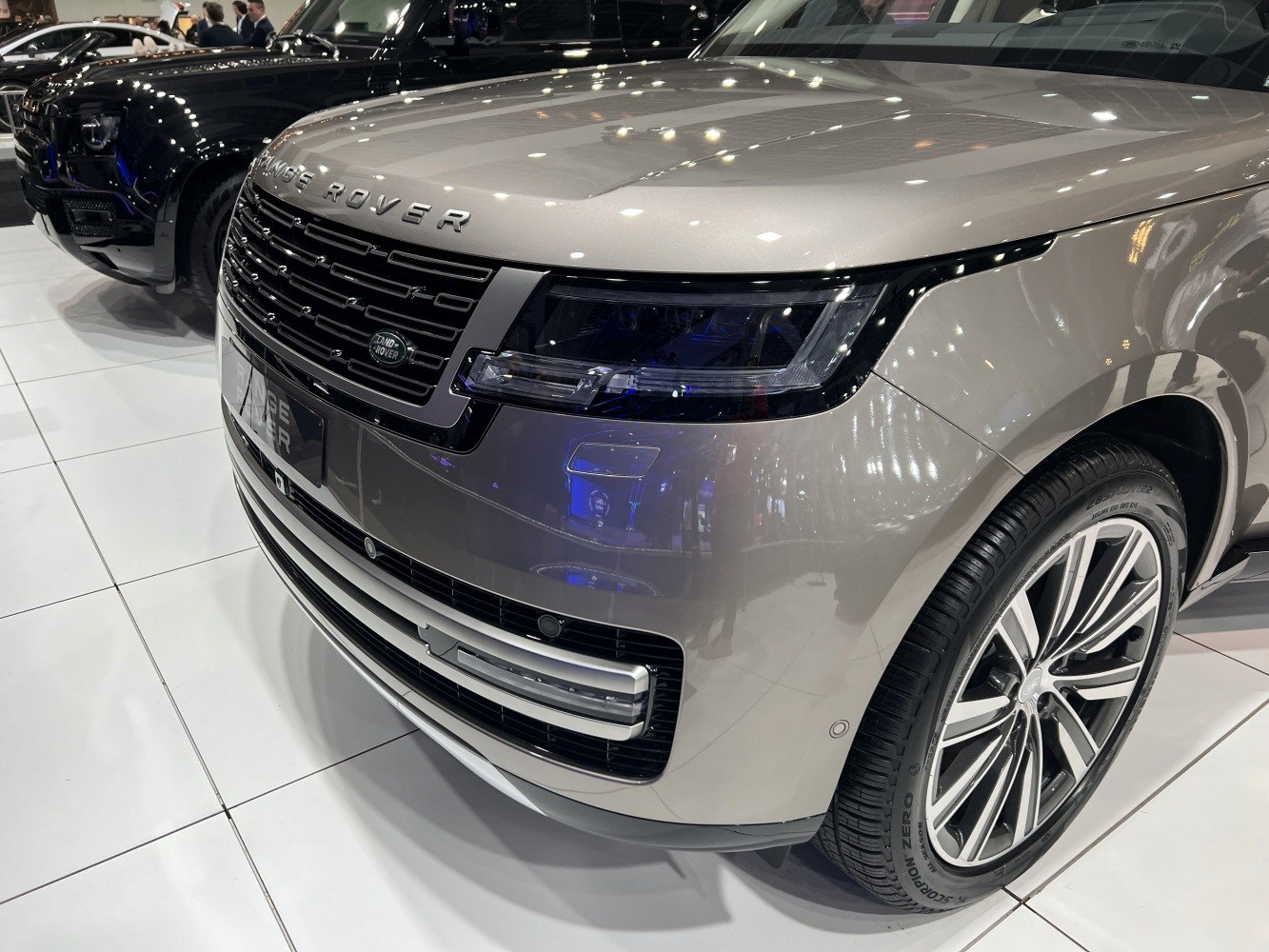 Close-up of front grille, headlights, and alloy wheel of a luxury SUV.