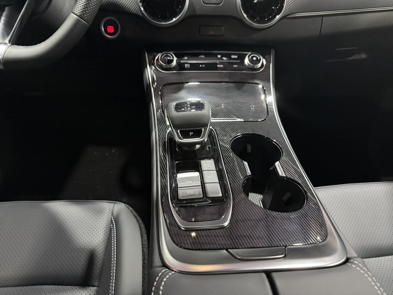 Center console with gear shifter and drive mode controls in carbon fiber trim