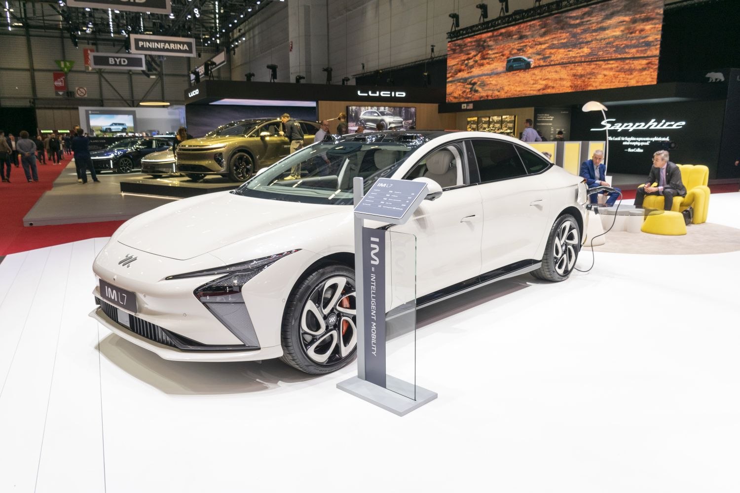 Electric sedan with sleek design and charging station at auto show