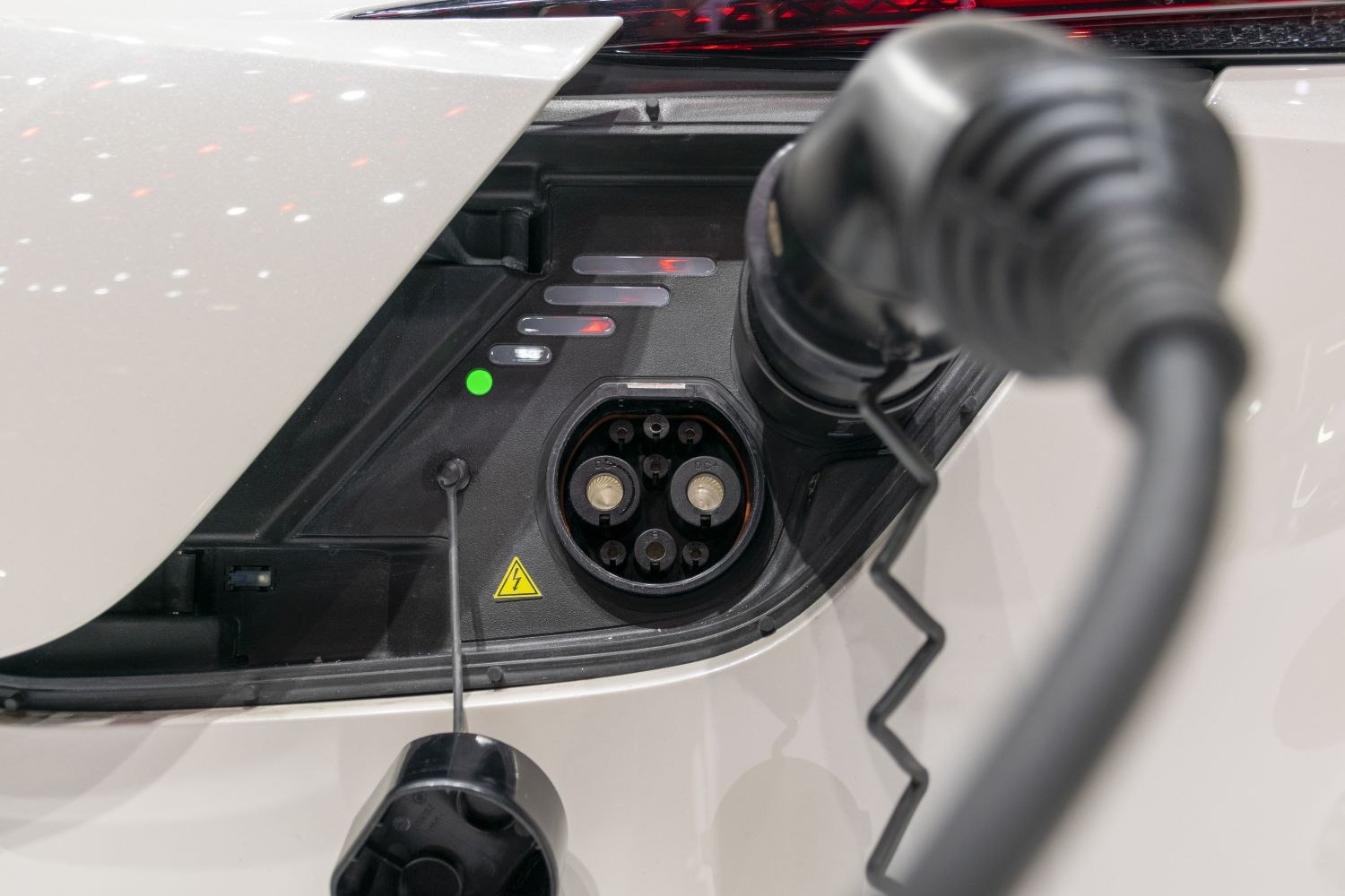 Close-up of electric vehicle charging port with cable and indicator lights