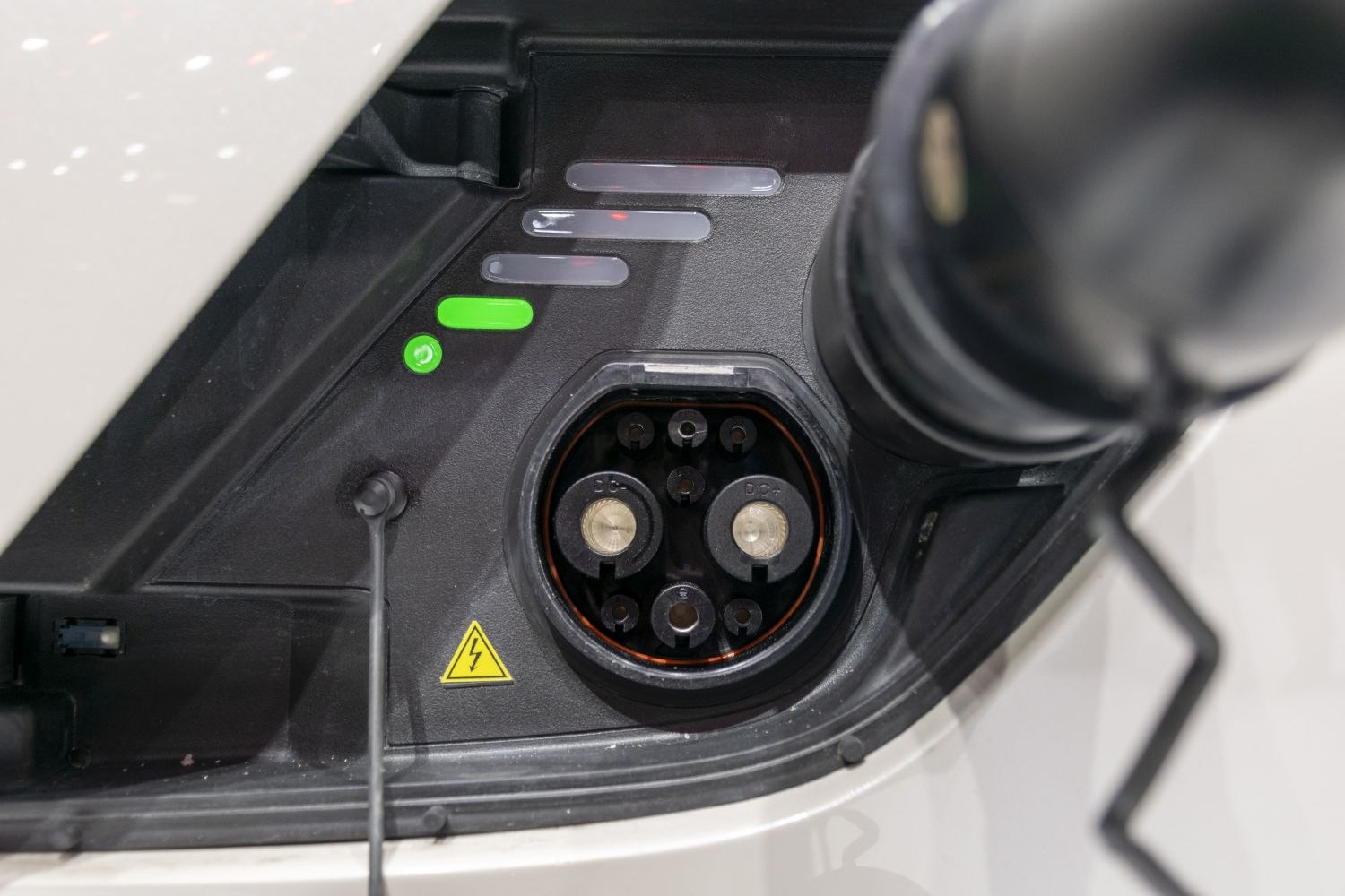 Close-up of electric vehicle charging port with plug interface and LED indicators