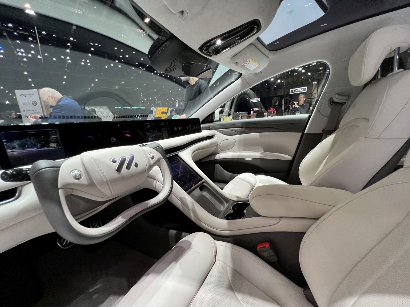 Yoke-style steering wheel and wide digital dashboard in luxury car interior.
