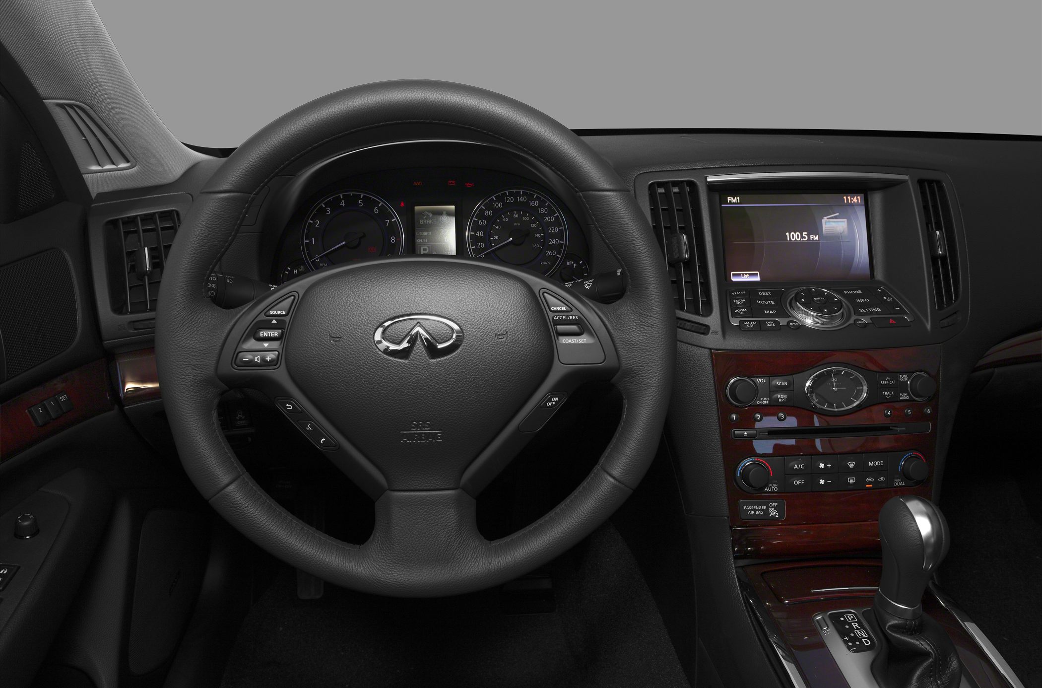 Steering wheel, dashboard, infotainment system with wood trim and gear shifter.