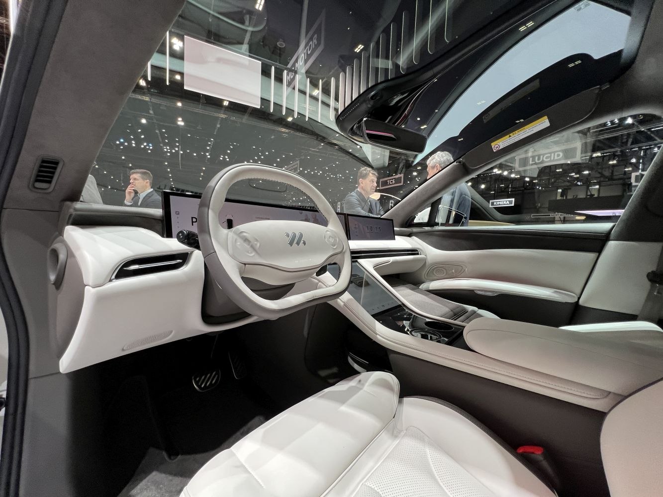 Minimalist white leather interior with digital dashboard and unique steering wheel design