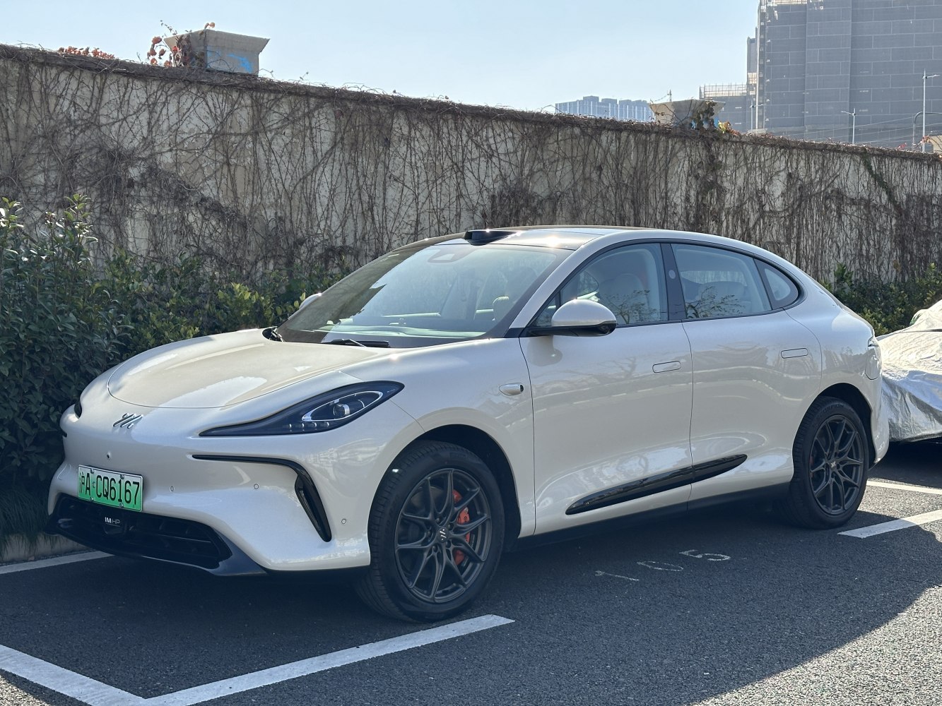 White electric sedan with black multi-spoke wheels and red brake calipers.