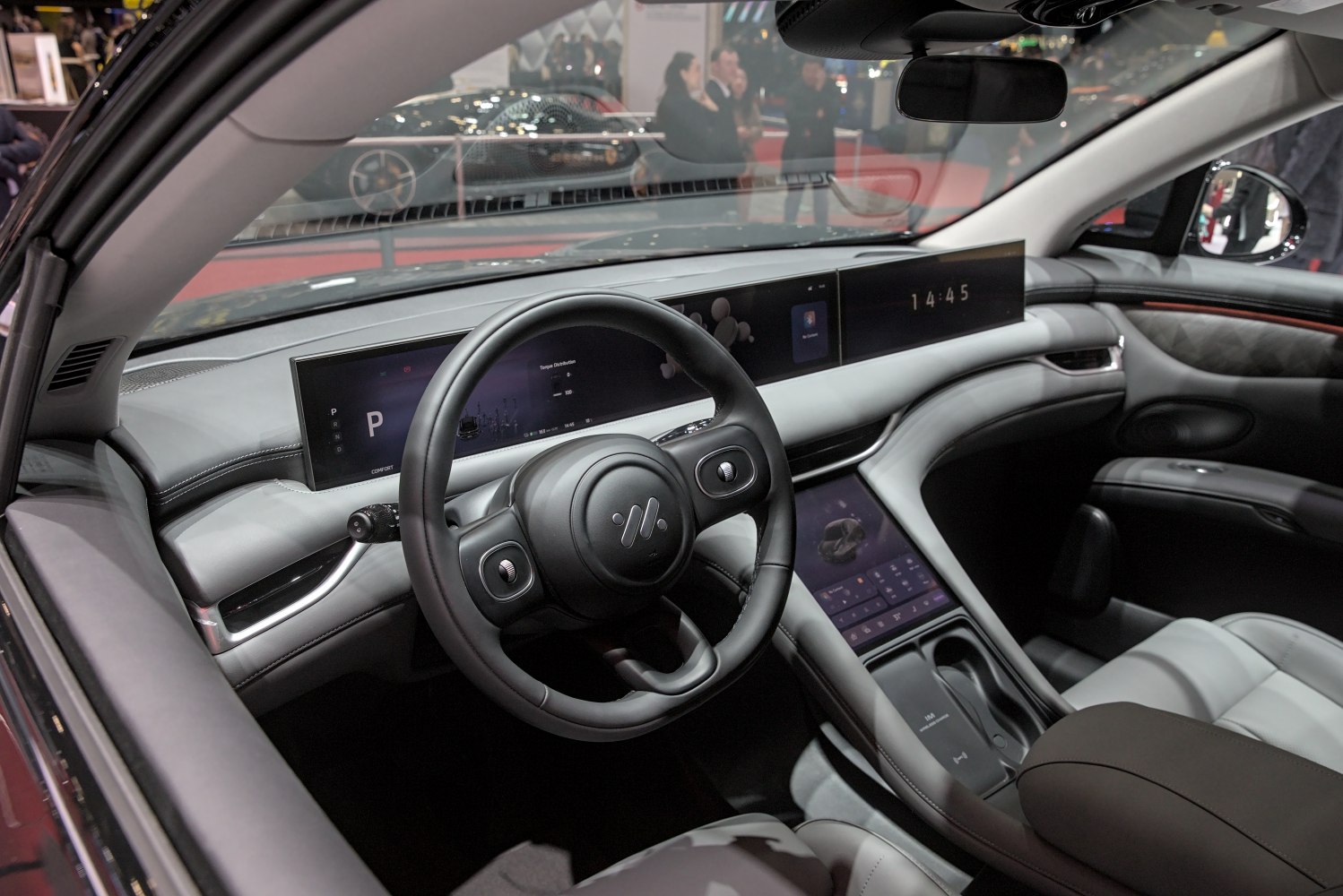 Dual wide digital displays and modern steering wheel inside a car interior.