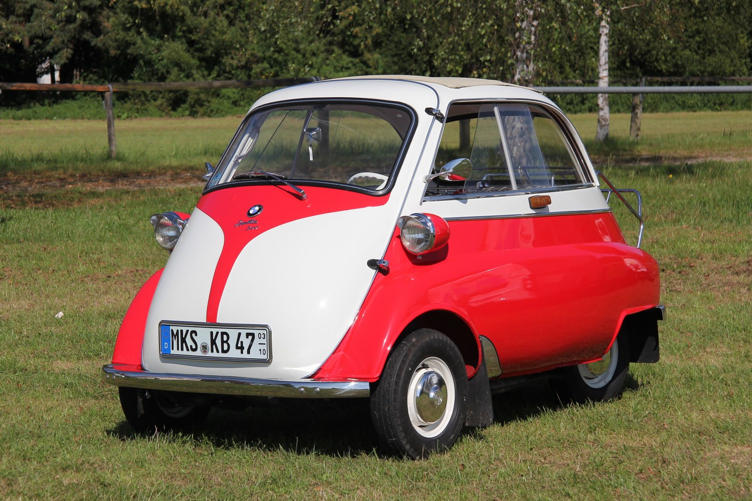 Compact vintage microcar with front-opening door and three-wheel design.