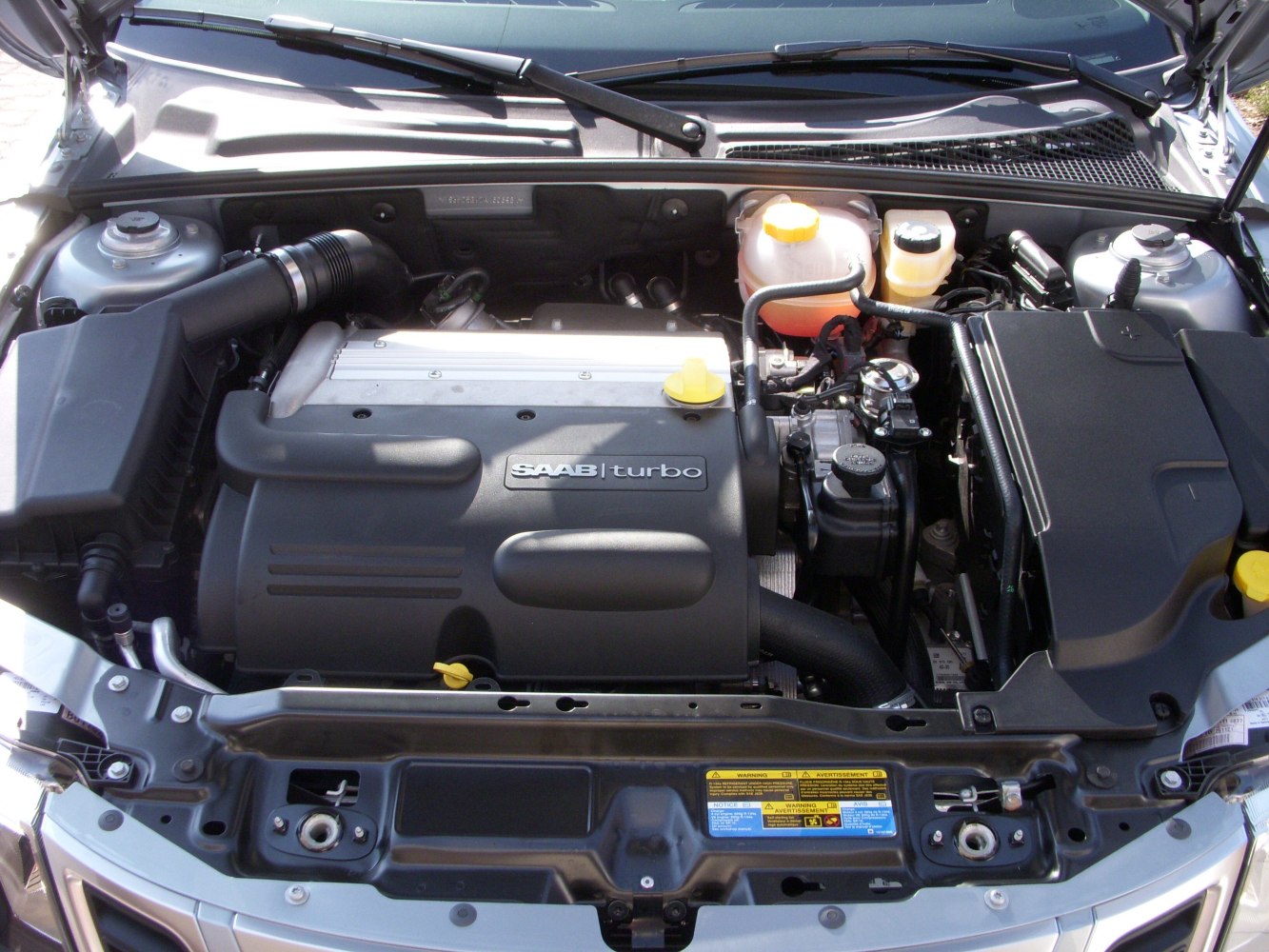 Turbocharged car engine bay with visible components and yellow caps
