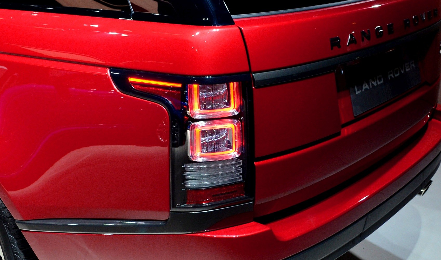 Rear tail light and Range Rover badge on red SUV.