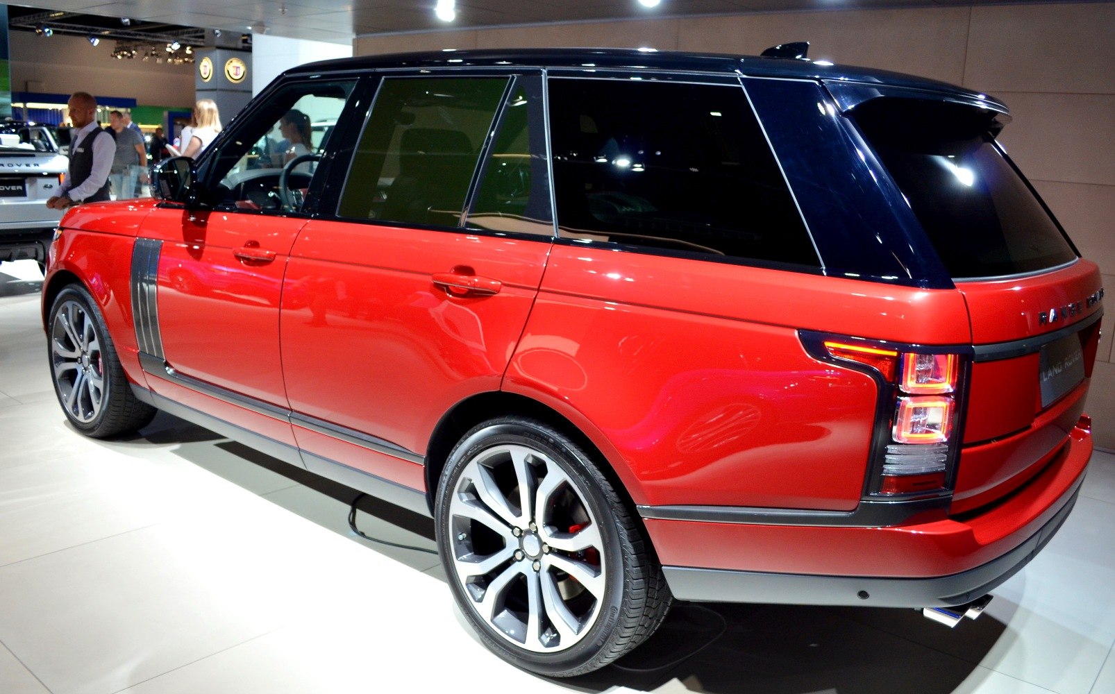 Red SUV with black roof, alloy wheels, and rear light cluster