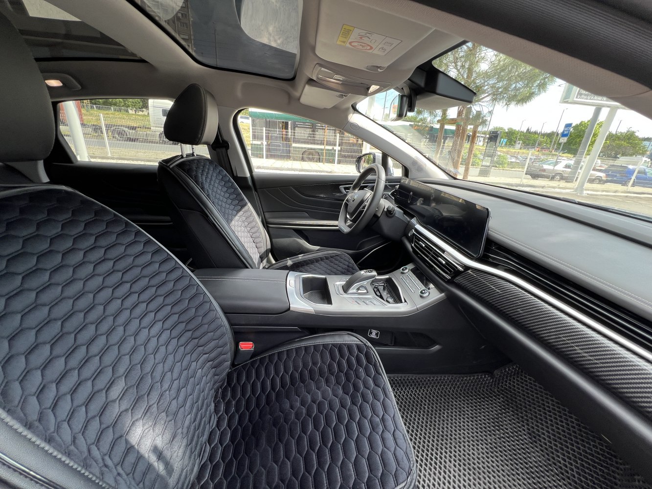 Modern seats with hex pattern and panoramic sunroof inside a vehicle